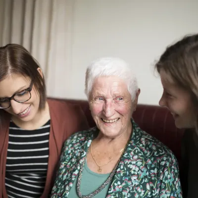 Une grand-mère sourit à côté de ses deux petites-filles.