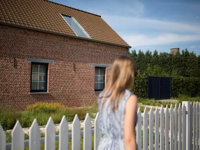 Une jeune femme devant une maison située en Flandre en France