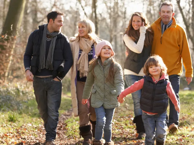 Une famille (grands-parents, parents et enfants) se promène dans les bois en France, sereins car leur planification de succession a été réglée par leur notaire.