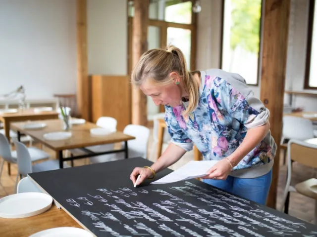 Une entrepreneuse prépare la carte son restaurant après avoir adapté les statuts de son entreprise.