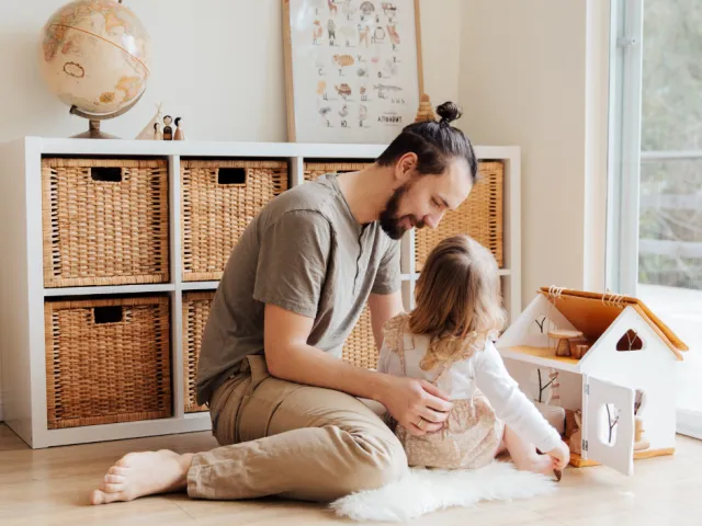 Un père joue avec sa fille dans sa chambre.
