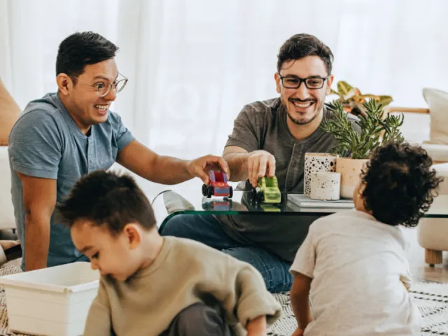 Un couple joue dans le salon avec leurs enfants après avoir rédigé et signé un contrat de cohabitation chez leur notaire.