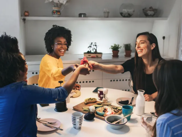 Quatre colocataires en France profitent d'un bon repas tous ensemble après avoir rédigé un pacte de colocation clair pour éviter tout conflit.